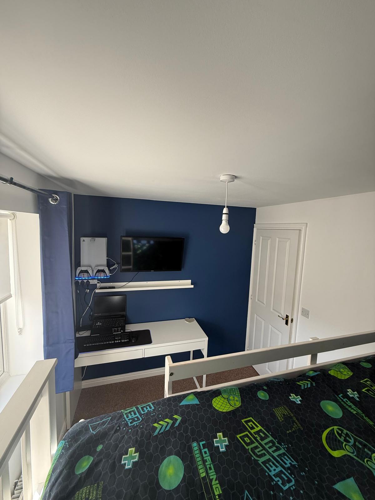 Bedroom feature wall painted navy blue with TV mounted